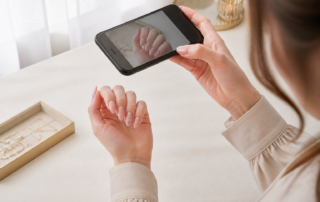 スマホでロングネイルを撮影する女性の手元